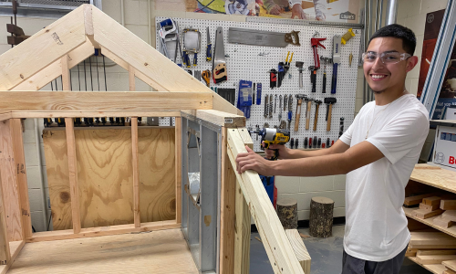   Jaime Torres holds a drill while standing to the right of a project he constructed